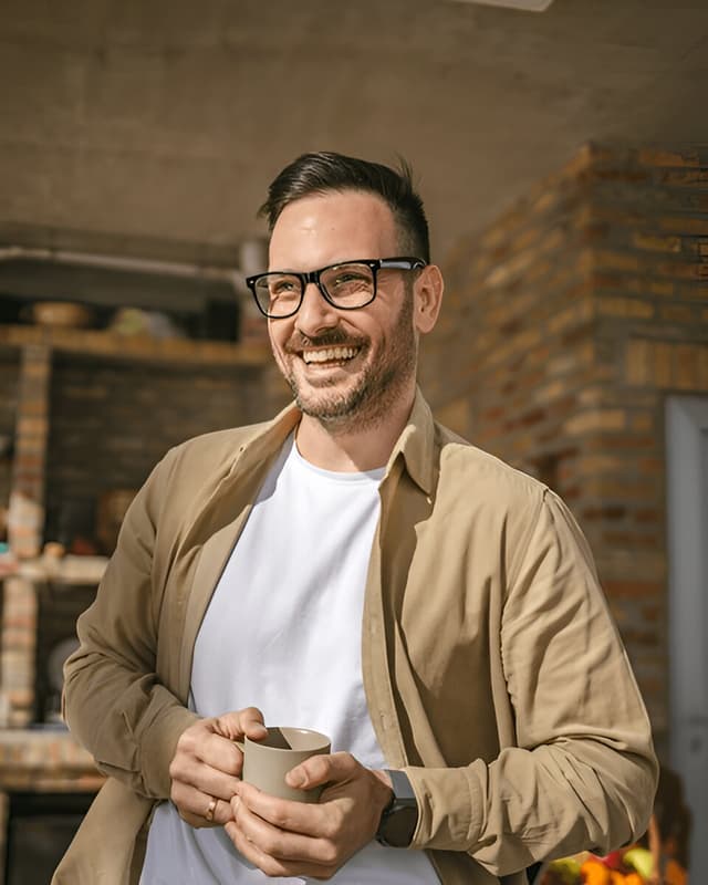 Um homem com um copo de café em mãos.
